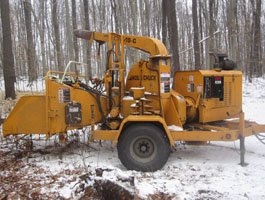 Industrial wood chipper processing branches on a job site